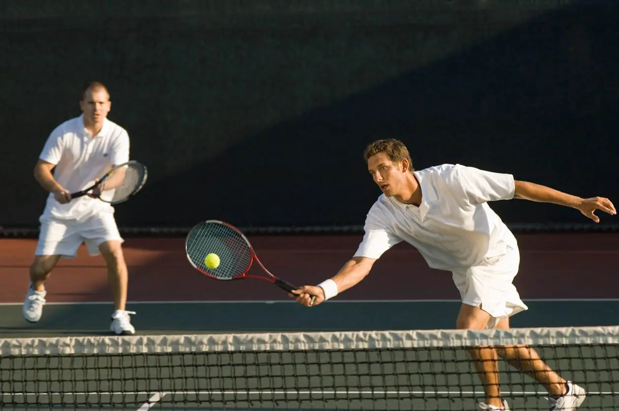 Two men playing tennis on an RV court.