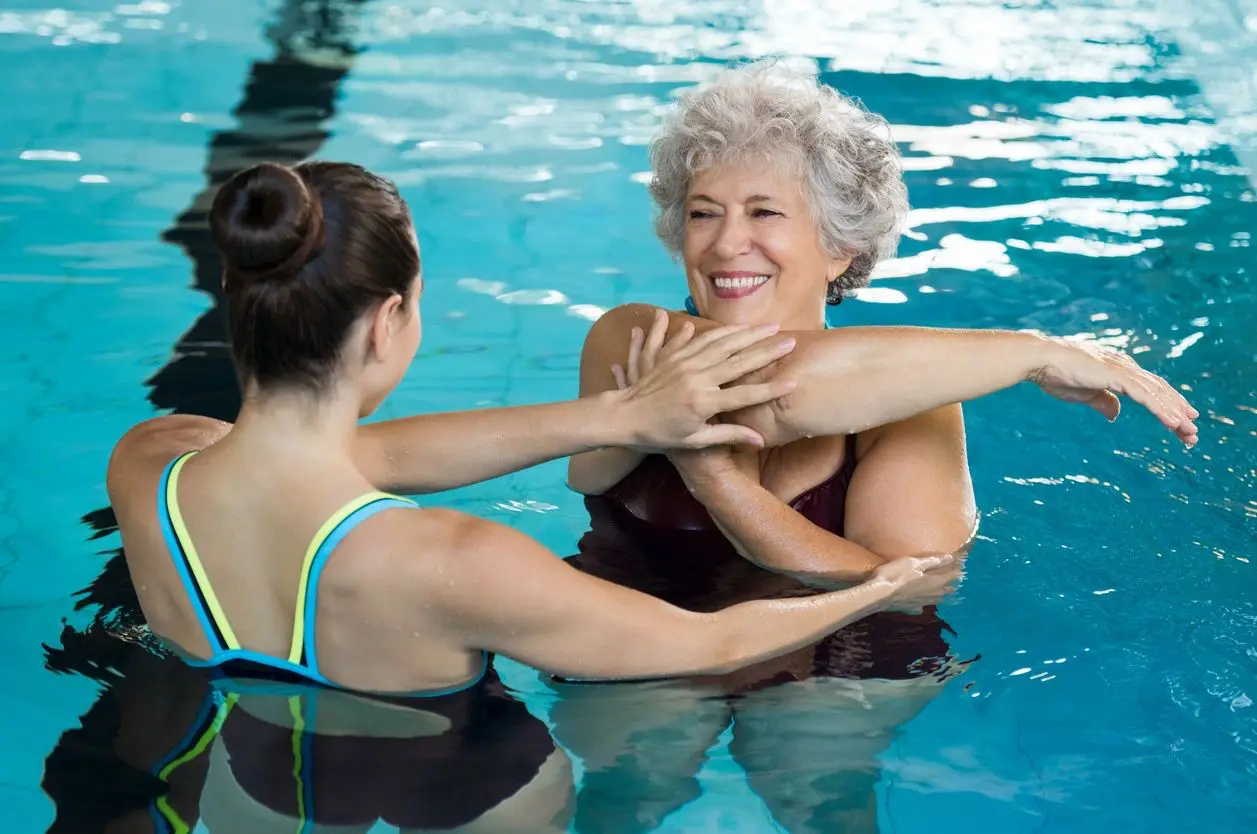 A woman and an older woman enjoying their time in a swimming pool adjacent to their RV.