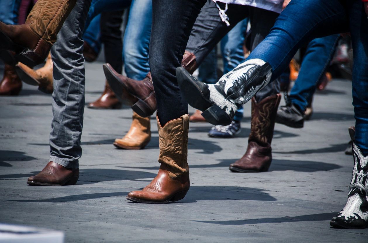 A group of people wearing cowboy boots on a street.