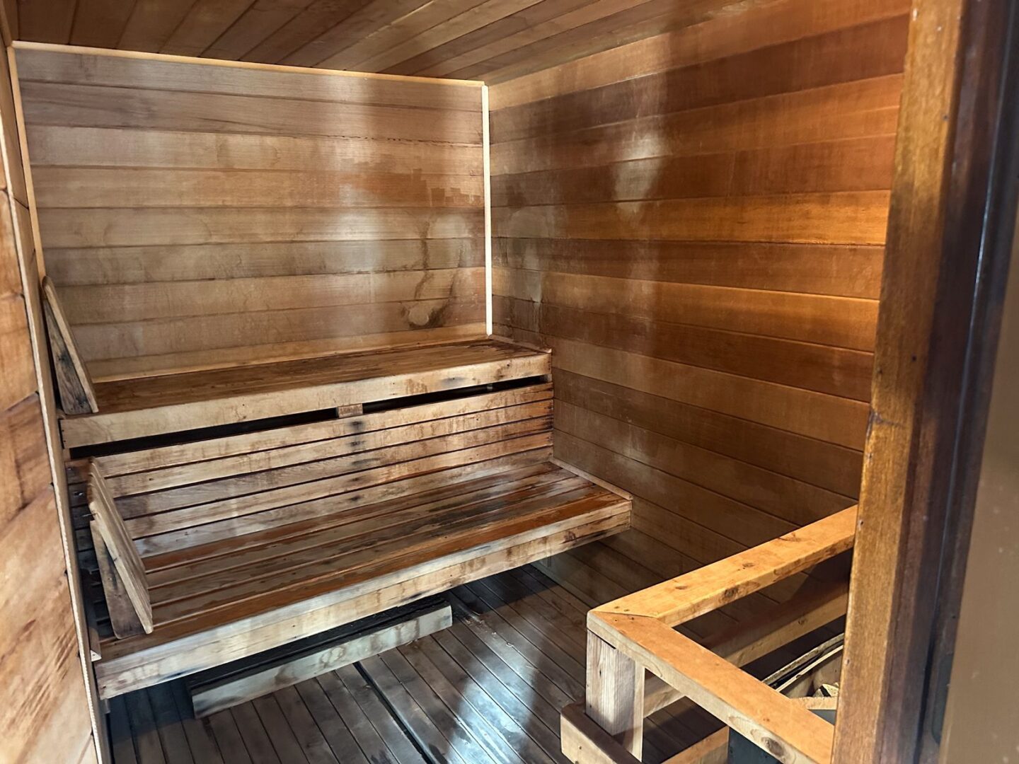 A sauna room with wooden benches and a wooden floor.