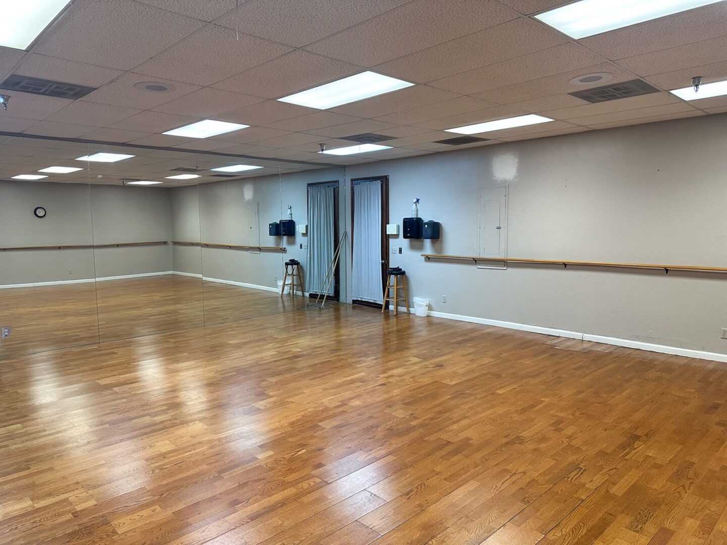 An empty dance studio with wooden floors and mirrors.