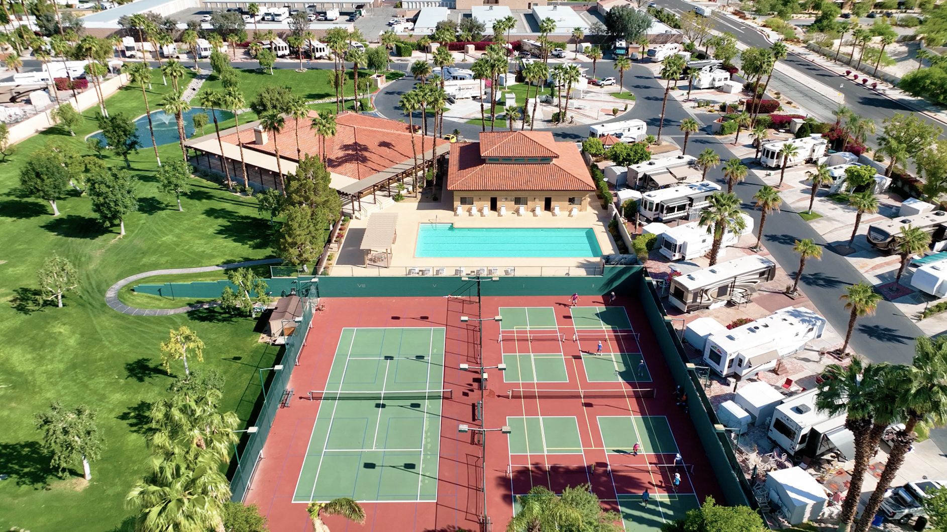 An aerial view of an rv park with a tennis court.