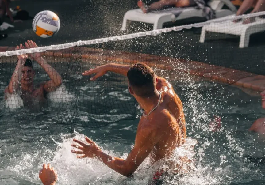 A group of men playing volley ball in a pool.